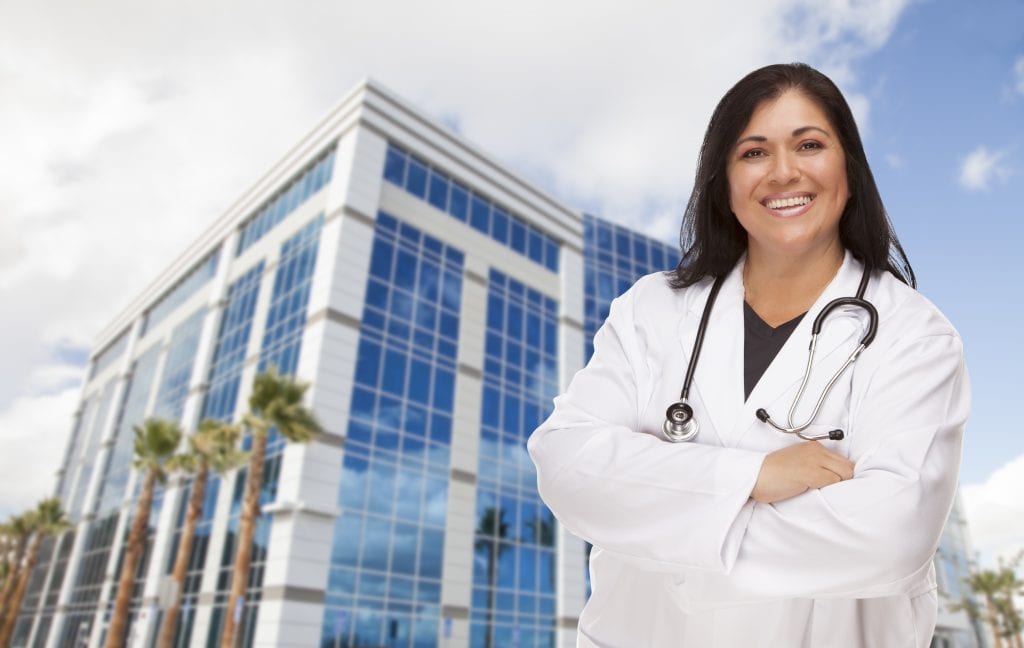 Attractive Hispanic Doctor Or Nurse In Front Of Corporate Building